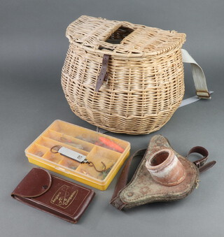 A basket fishing creel containing a collection of spinners and lures, a leather Baldrick and a small salmon spring balance 