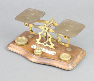 A pair of brass letter scales marked Made in England complete with weights, raised on a shaped mahogany base 7cm x 18cm x 8cm 