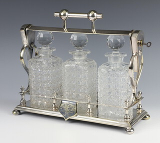 A Victorian silver plated 3 bottle tantalus, with 3 associated glass decanters and stoppers, complete with key, on bun feet 30cm h x 36cm w x 13cm d
