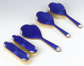 A five piece blue and white enamelled back dressing table set comprising pair of hair brushes, pair of clothes brushes and a hand mirror 