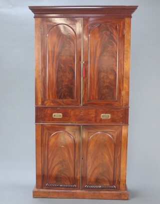 A Victorian mahogany bookcase on cabinet, the upper section with moulded cornice, the shelved interior enclosed by a pair of arched panelled doors, the base with drawer above cupboards enclosed by panelled doors, raised on a platform base 205cm h x 110cm w x 35cm d 