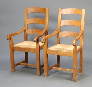 A pair of hardwood ladder back carver chairs with rush seats raised on square supports, H framed stretchers 105cm h x 52cm w x 55cm d (seat 35cm x 27cm, pitting to the bar backs, some wear to the rush seats) 