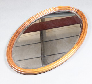 An Edwardian oval bevelled plate wall mirror contained in a shaped mahogany frame 83cm x 53cm (splits to top and bottom of frame) 