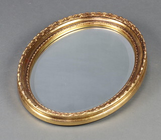 An oval bevelled plate mirror contained in a decorative gilt frame 46cm x 35cm 