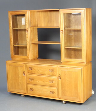 An Ercol light elm Windsor sideboard/dresser, the raised back fitted 2 cupboards with adjustable shelves enclosed by bevelled plate panelled doors, the centre section with recess above 3 drawers and pair of cupboards 162cm h x 156cm w x 44cm d (light scratches to the left hand side of the top cupboard)
