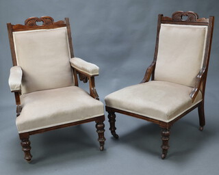 An Edwardian carved walnut show frame open arm chair upholstered in mushroom coloured material, raised on turned supports 100cm h x 63cm w x 64cm d (seat 29cm x 33cm, caster loose) together with a matching nursing chair 97cm h x 60cm w x 61cm d (seat 29cm x 38cm) 