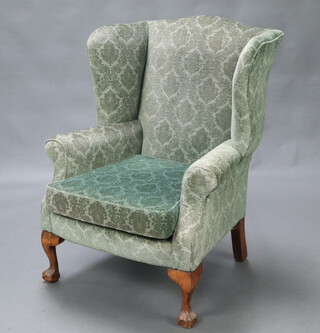 A Georgian style winged armchair upholstered in green material, raised on cabriole, ball and claw supports 102cm h x 74cm w x 61cm d (seat 30cm x 38cm) 