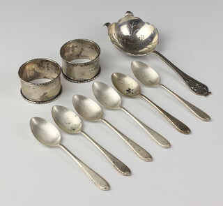 A pair of silver napkin rings Birmingham 1952, 6 teaspoons and a tea strainer 154 grams 