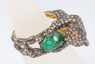 A yellow metal diamond set ring in the form of a bear with ruby eyes holding a cabochon cut emerald, 8.7 grams, size N 1/2, diamonds approx. 1.85ct, rubies 0.04ct, emerald 3.25ct
