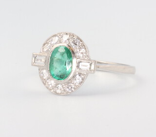 A white metal stamped Plat. oval emerald and baguette and brilliant cut diamond cluster ring, the emerald 0.95ct, the diamonds 0.35ct, size O 1/2, 3.6 grams 