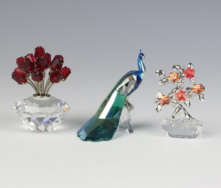 A Swarovski figure of a peacock sitting on a trunk 8cm, a ditto of a vase of flowers 5.5cm and a vase of tulips 6cm, all boxed 
