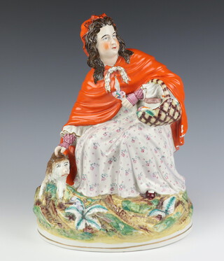 A Victorian Staffordshire figure of Little Red Riding Hood with a wolf at her feet, raised on an oval base 37cm h 