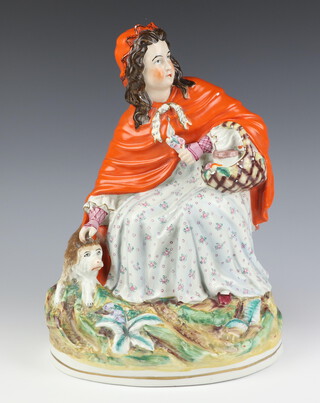 A Victorian Staffordshire figure of Little Red Riding Hood with a wolf at her feet, raised on an oval base 37cm h 