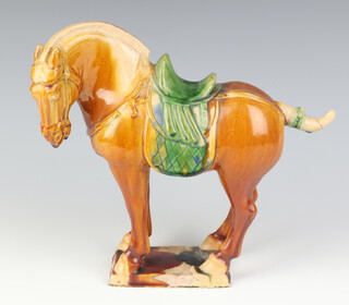 A Chinese Tang style figure of a standing horse in brown and green glaze, raised on a rectangular base 23cm 