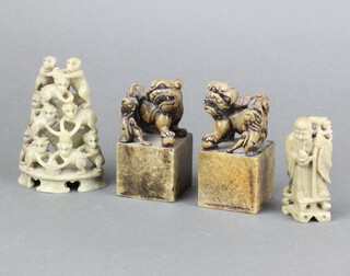 A pair of carved marble paperweights surmounted by Dogs of Fo 9cm x 4cm x 4cm, a carved soapstone figure of a standing Deity 8cm x 2cm x 2cm and a pierced soap stone figure group of a pyramid of monkeys 11cm x 7cm x 3cm 