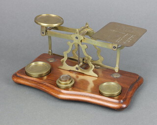 A set of brass postage scales on a mahogany base together with 5 weights 