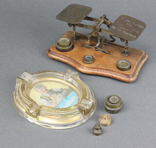 A pair of brass letter scales together with 5 weights on a shaped mahogany base 8cm x 19cm x 11cm together with 5 other brass weights, an oval glass advertising ashtray for Phillips Shoes and Soles 2cm x 15cm x 12cm 