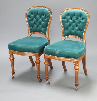A pair of Victorian mahogany show frame dining chairs, the seats of serpentine outline upholstered in green material, raised on turned and fluted supports, the bases impressed WS 91cm h x 48cm w x 48cm d (seat 30cm x 30cm)