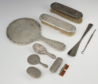 A silver backed hand mirror (rubbed marks), 2 silver backed brushes and a ditto shoe horn, a miniature plated brush set 