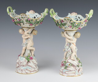 A pair of 19th Century German "Meissen" porcelain centre pieces with pierced baskets supported by cavorting children, raised on floral encrusted bases 28cm  