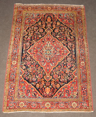 A Sarouk blue, white and red ground floral patterned Persian rug with central medallion within a multi row border 189cm x 130cm  