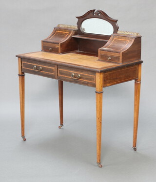 An Edwardian inlaid mahogany Carlton House style writing table with green inset leather writing surface, the raised back fitted an oval mirror with 2 stationery boxes to the sides, fitted drawers, the base fitted 2 long drawers, raised on square tapered supports with ceramic casters 108cm h x 91cm w x 48cm d  