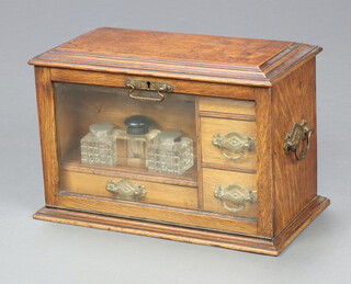 A Victorian oak stationery box with hinged lid and glass fall front revealing a stationery rack above 3 drawers, fitted 2 glass inkwells, 1 other associated inkwell and an associated glass bowl 23cm h x 36cm w x 20cm d 