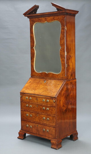 A Georgian figured walnut bureau bookcase, the associated upper section in the manner of Giles Grendey with broken neck pediment and dentil cornice, the originally shelved interior now fitted with pigeon holes enclosed by a shaped bevelled plate mirror panelled door, the with fall front revealing a well fitted interior above 4 drawers with replacement brass handles, raised on ogee bracket feet 122cm h x 75cm w x 45cm d 