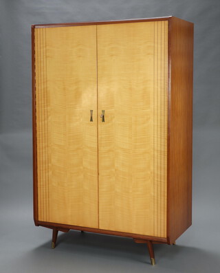 A mid-Century Maple & Co inlaid light wood bedroom suite comprising wardrobe enclosed by panelled door raised on square outswept supports with brass caps 179cm h x 115cm w x 58cm d together with a matching dressing table marked Maple with shaped plate mirror above 1 long and 3 short drawers, recess and undertier, raised on outswept supports 128cm h x 140cm w x 38cm d 