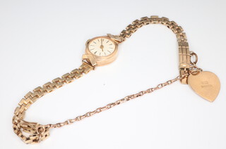 A lady's 9ct yellow gold wristwatch on a yellow metal bracelet with heart shaped charm