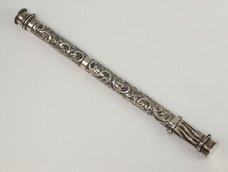 A Continental cylindrical repousse white metal needle and pin holder decorated with scrolls 22cm 