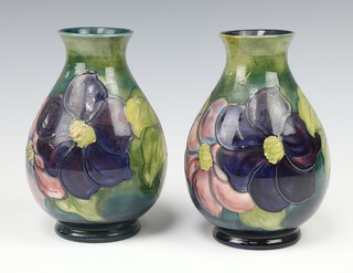 Moorcroft, a pair of green ground anemone pattern vases, the bases impressed Moorcroft Made in England and with paper label, potter to H M Queen Mary, 20cm h x 10cm diam. 