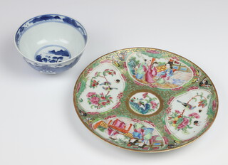 A 19th Century Chinese blue and white rice bowl decorated trees and buildings, the base with 4 signature mark 11cm and a circular Canton famille rose porcelain plate with panel decoration of figures and birds 20cm  