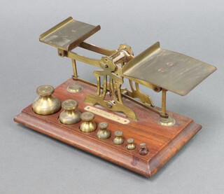 A pair of brass letter scales together with 7 brass bell weights raised on a mahogany case 11cm x 24cm x 13cm 