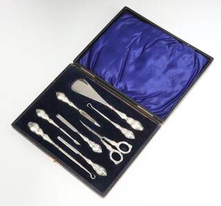 A cased set of Edwardian silver mounted dressing table accessories including button hooks, shoe horn, nail file, tweezers, manicure items and scissors, Birmingham 1905 and 1910 
