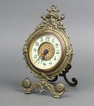 A Victorian 8 day timepiece with 9cm enamelled dial, Roman numerals contained in a gilt metal easel case surmounted by a mask 22cm h x 14cm 