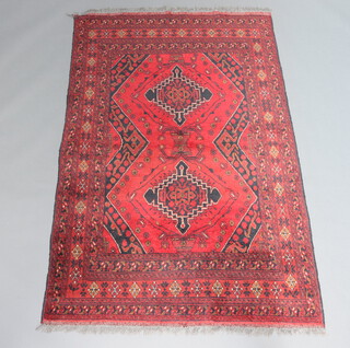 A red and black ground Afghan rug with 2 medallions to the centre within multi row border 197cm x 127cm 