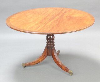 A circular Regency crossbanded mahogany snap top breakfast table raised on a turned column and tripod base, brass caps and casters 71cm h x 121cm diam. 