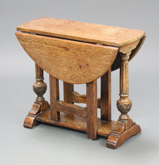 A 17th Century style carved oak oval drop flap gateleg tea table, raised on cup and cover supports 59cm x 59cm x 22cm 