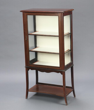 An Edwardian inlaid mahogany display cabinet fitted shelves enclosed by glazed panelled door, raised on outswept supports with undertier 125cm h x 63cm w x 33cm d 