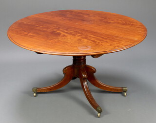A Georgian circular mahogany snap top breakfast table raised on a turned column tripod base, brass caps and casters 130cm diam. 