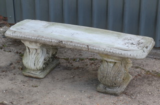 A well weathered rectangular concrete garden bench on shaped supports 39cm h x 121cm w x 37cm d 
