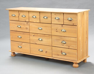 A sideboard/chest of 6 short and 9 long pine drawers, raised on bun feet (contact and ring marks in places) 81cm h x 122cm w x 40cm d  

