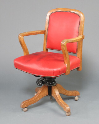 An Art Deco oak open arm revolving office chair, the seat and back upholstered in red material 93cm h x 58cm w x 47cm d  