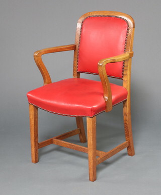 A 1930's light oak open arm office chair, seat and back upholstered in red material, raised on square supports with H framed stretcher 93cm h x 59cm w x 46cm d 