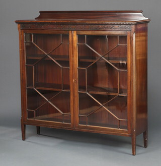 A Chippendale style mahogany bookcase with raised back and blind fretwork decoration, enclosed by glazed panelled doors on square tapered supports 122cm h x 121cm w x 33cm d 