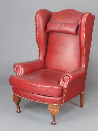 A Georgian style winged armchair upholstered in red material, raised on cabriole supports 127cm h x 87cm w x 73cm w (seat 38cm x 49cm) 