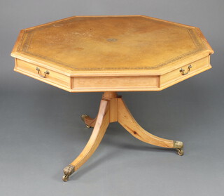 A Georgian style octagonal pine drum table with brown leather inset top, fitted 4 frieze drawers, raised on a turned column and tripod base ending in brass paw casters 75cm h x 112cm diam. 