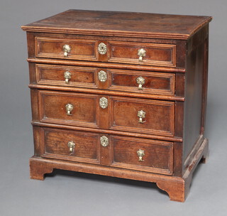 A Queen Anne oak chest of 4 long drawers with original brass pin drop handles, crowned brass escutcheons and raised on bracket feet 84cm h x 85cm w x 56cm d 