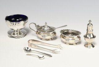An Edwardian embossed silver mustard and salt condiment set (the salt without liner) Birmingham 1902, a circular pierced silver salt with blue glass liner, silver pepperette,  a sauce spoon and mustard spoon, pair of silver plated ice tongs, weighable silver 144 grams  